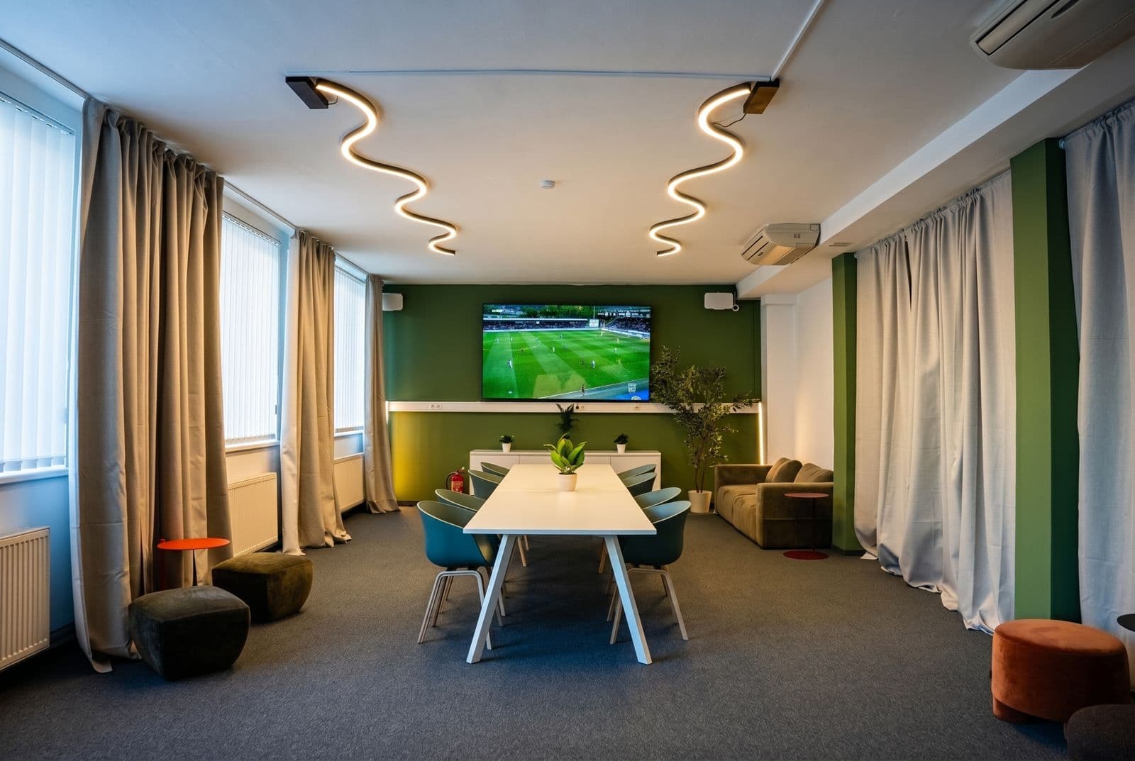 Lounge der Football Factory mit Großbildschirm, Sitzecke und Couch für Firmenevents