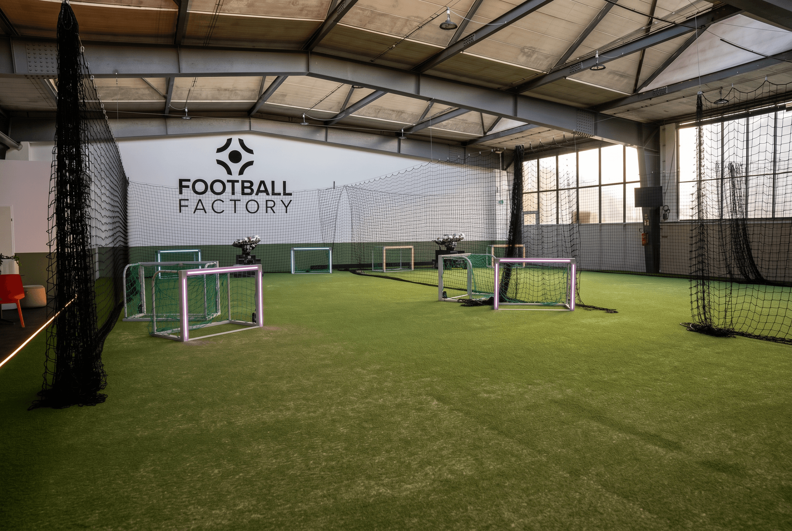Trainingsfläche der Football Factory mit Kunstrasen, beleuchteten Mini-Toren und Wandlogo